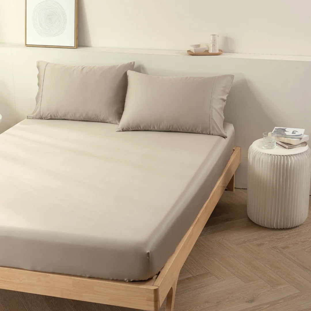 A neatly made bed with Linenly taupe bamboo fitted sheets in a minimalist bedroom setting, transforming it into a luxury sleep sanctuary.