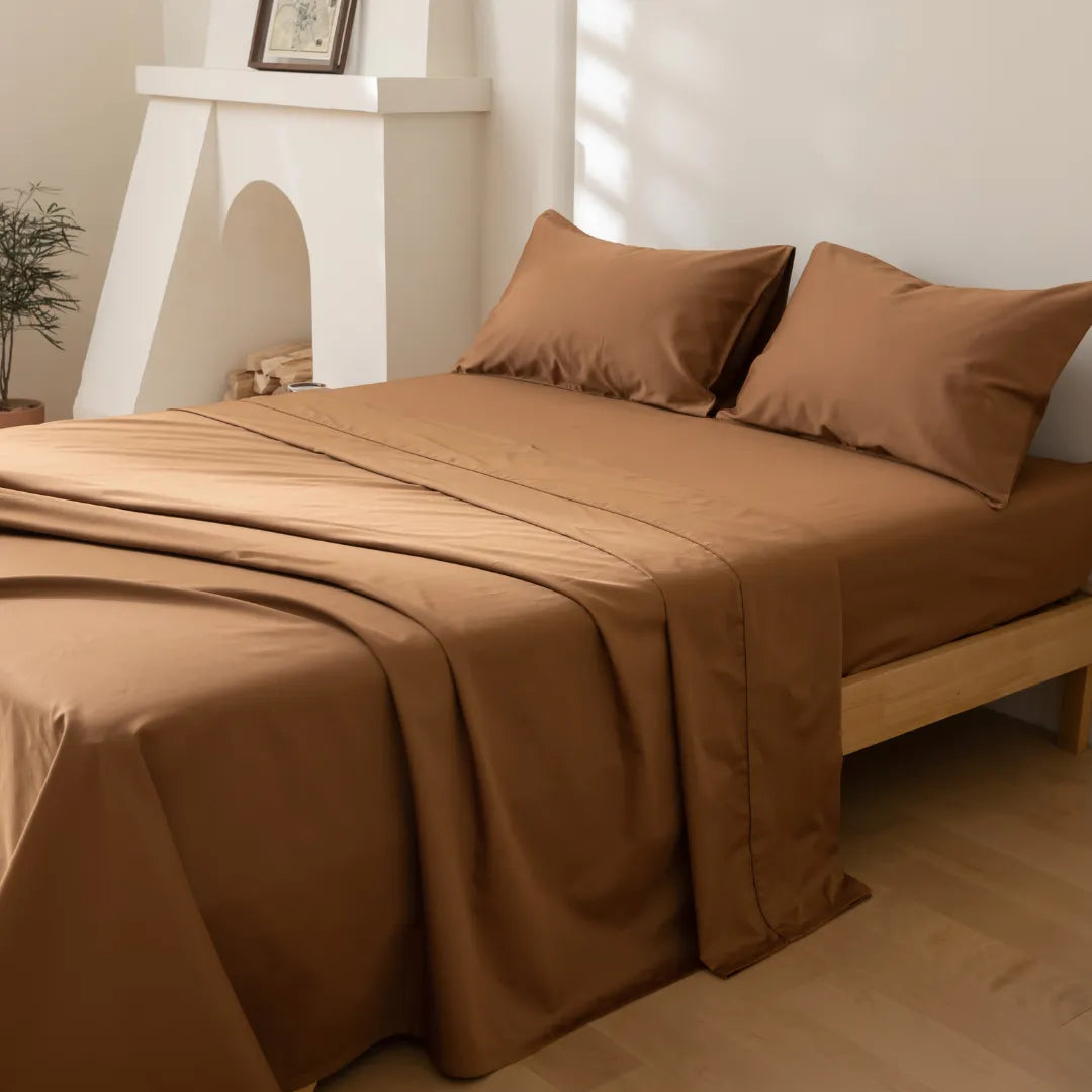 A neatly made bed with a Linenly Luxe Sateen Flat Sheet in Terracotta and pillowcases, set against a serene minimalist room decor, inviting a cozy and restful ambiance.