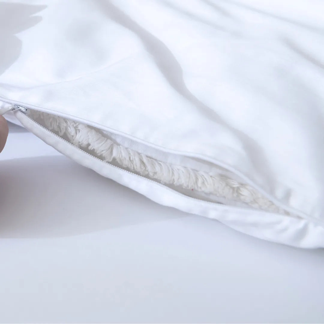 A close-up view of a white pillow with a zipper, partially unzipped to reveal the cushioning inside, encased in a Linenly Luxe Sateen Quilt Cover - White.