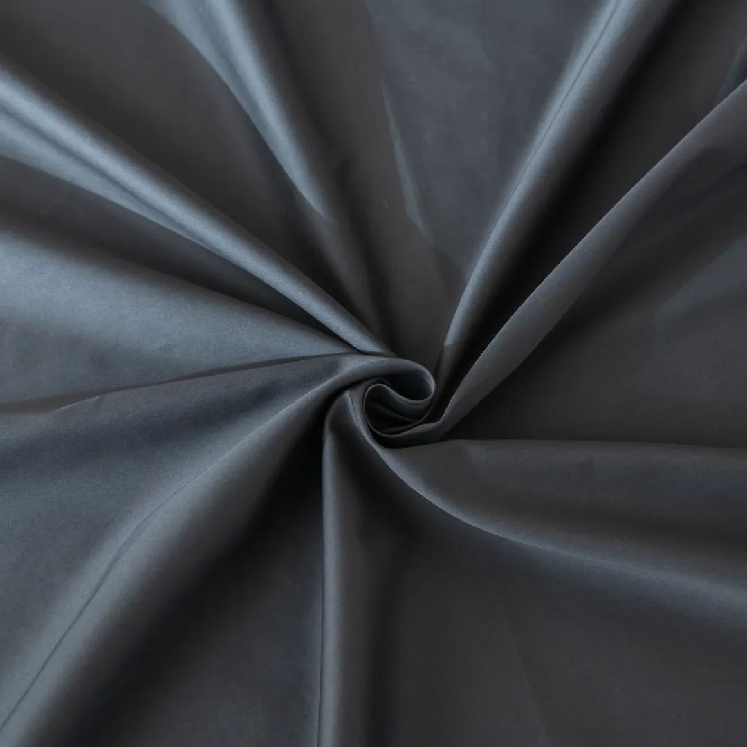 A close-up of a twisted Linenly Luxe Sateen Sheet Set - Charcoal fabric with soft folds radiating from the center.