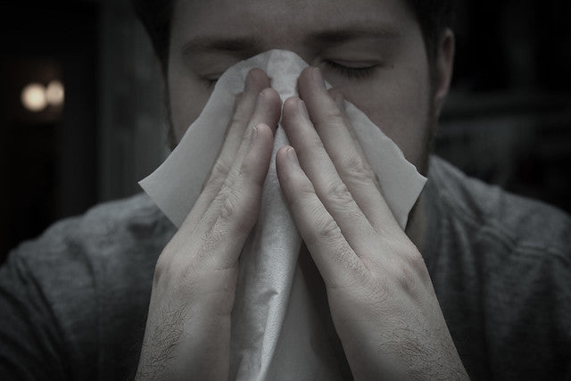 a man sneezing and holding a tissue in the nose
