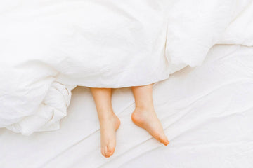 a person  lying in bed with the feet showing under a white bed  sheet