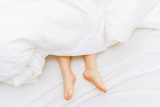 a person lying in bed with the feet showing under a white bed sheet