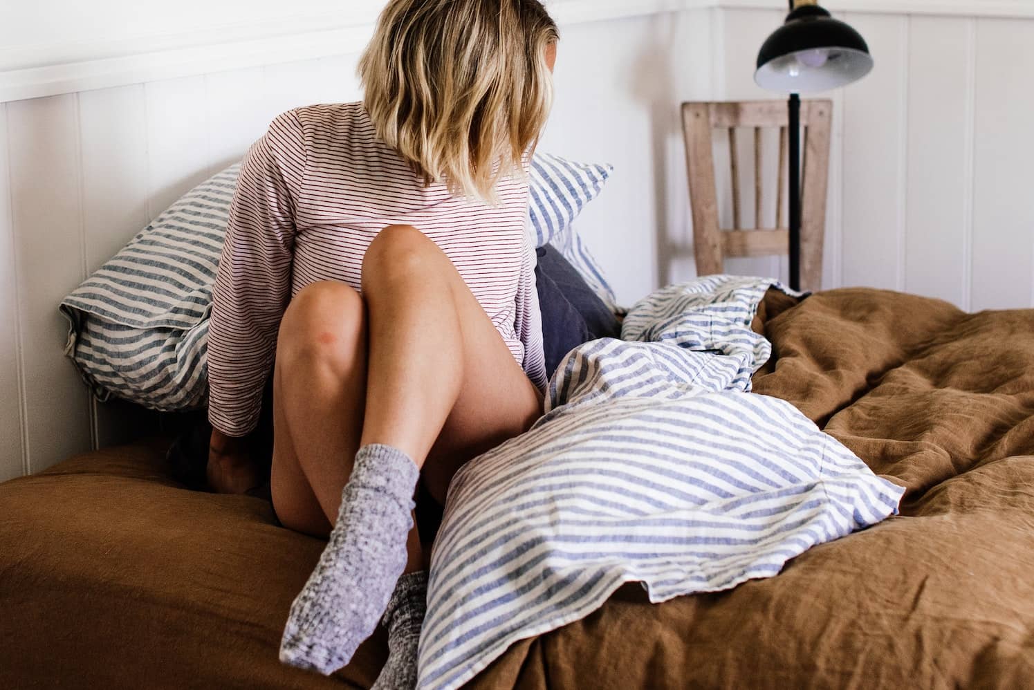 A woman wearing socks sitting on bed