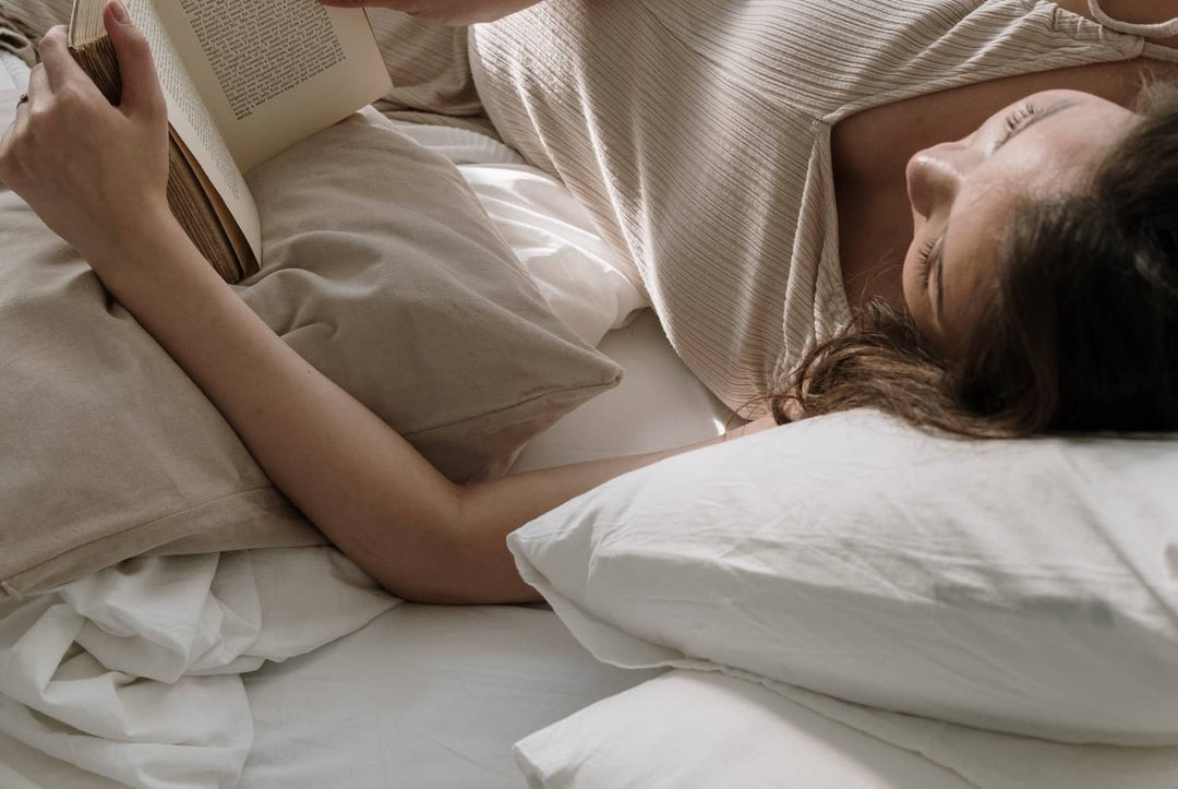 a woman lying in bed while reading a book