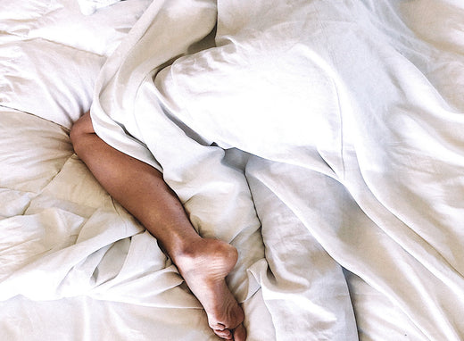 a person in bed covered with bamboo bed sheet with a leg visible