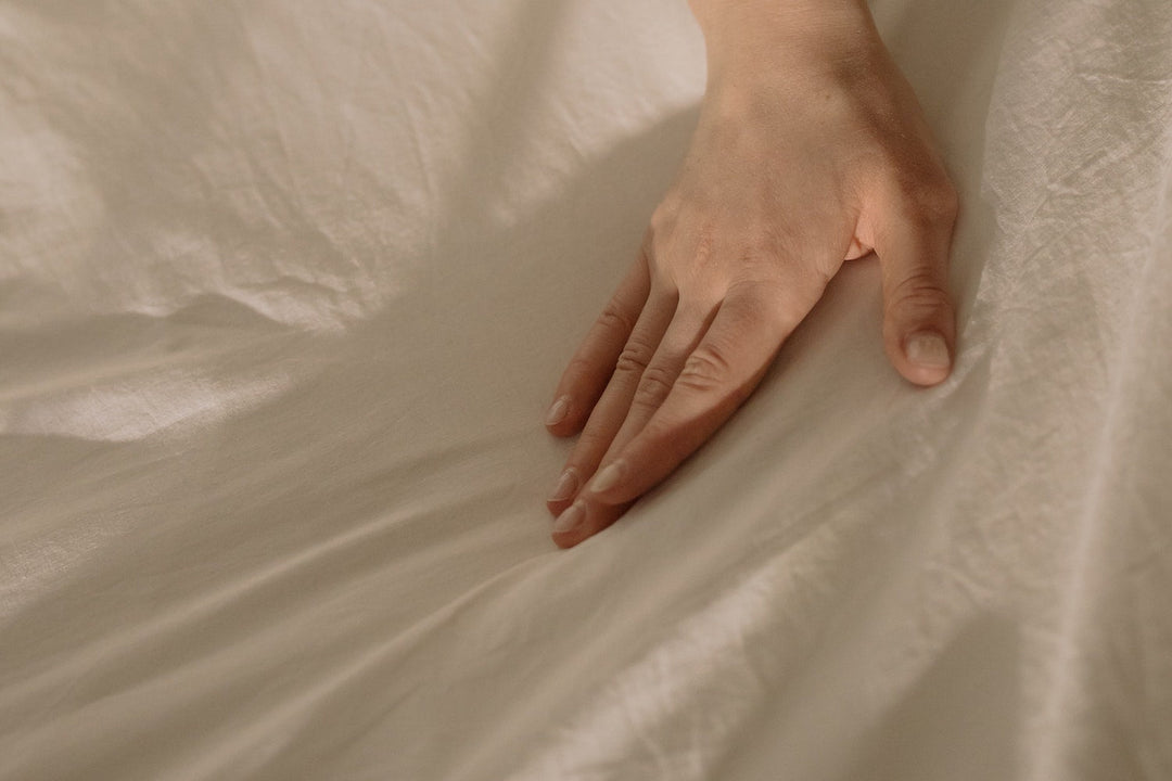 a hand touching a bed sheet