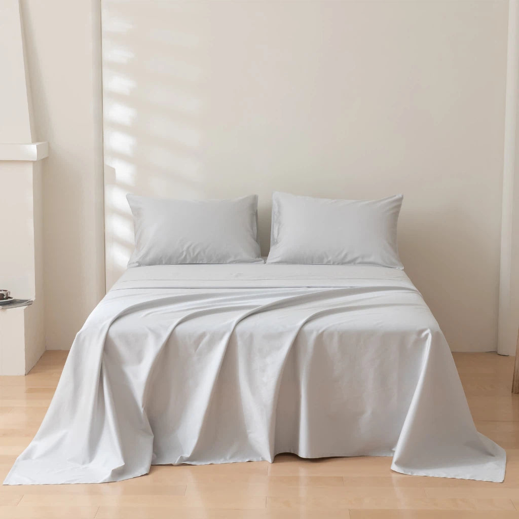 A neatly made bed with a plain white bedding set in a bright and minimalist room.