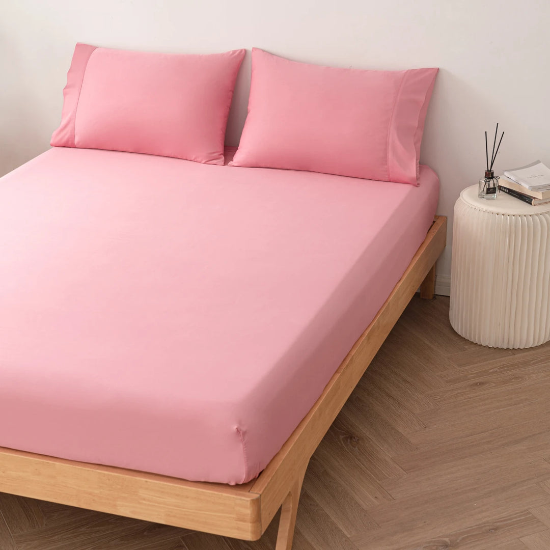 A neatly made bed with Linenly's Bamboo Fitted Sheet in Light Rose in a minimalistic room setting.