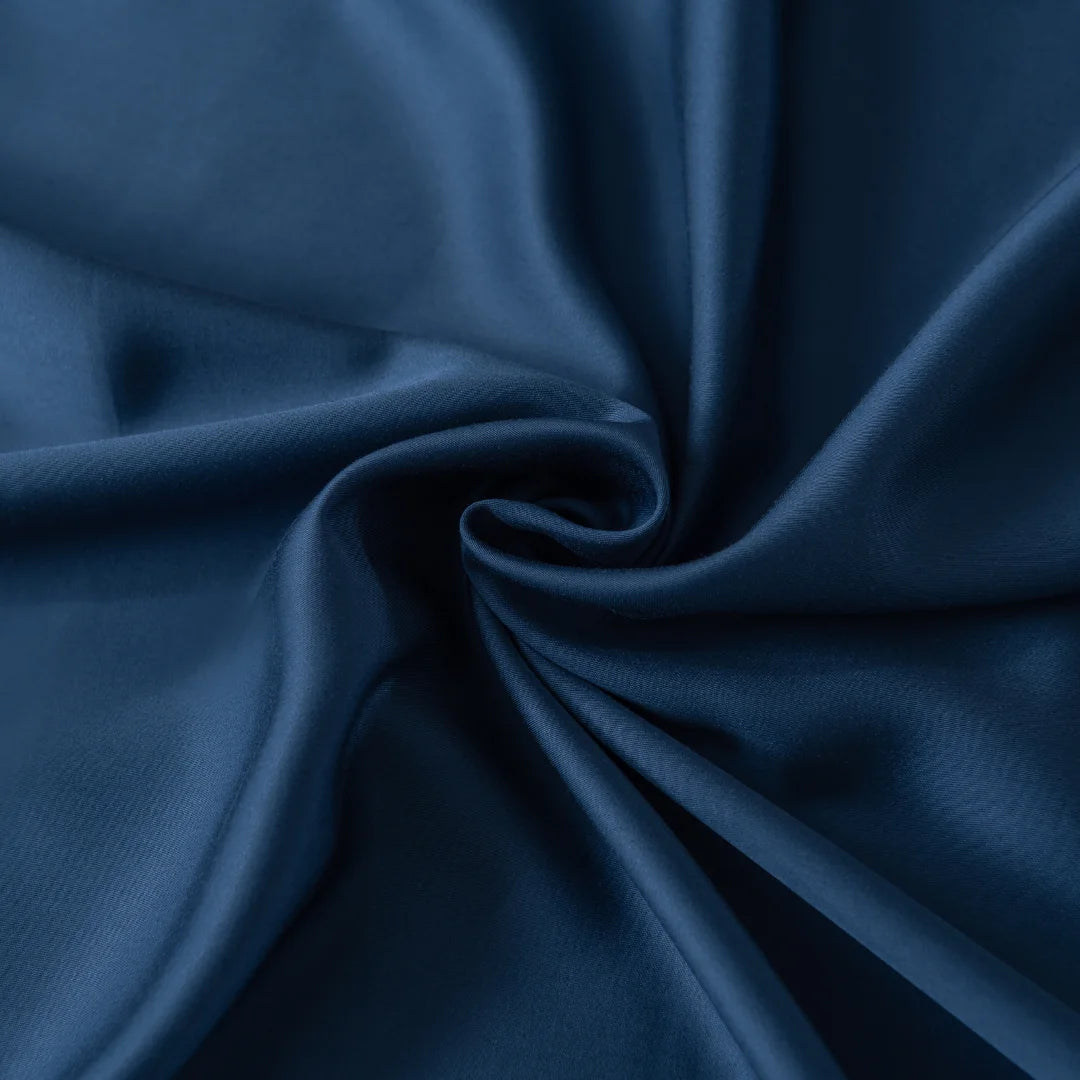 Close-up of the luxurious Bamboo Fitted Sheet - Midnight by Linenly, showcasing its dark blue satin fabric with soft waves and folds. The smooth texture and deep color exude elegance and softness.