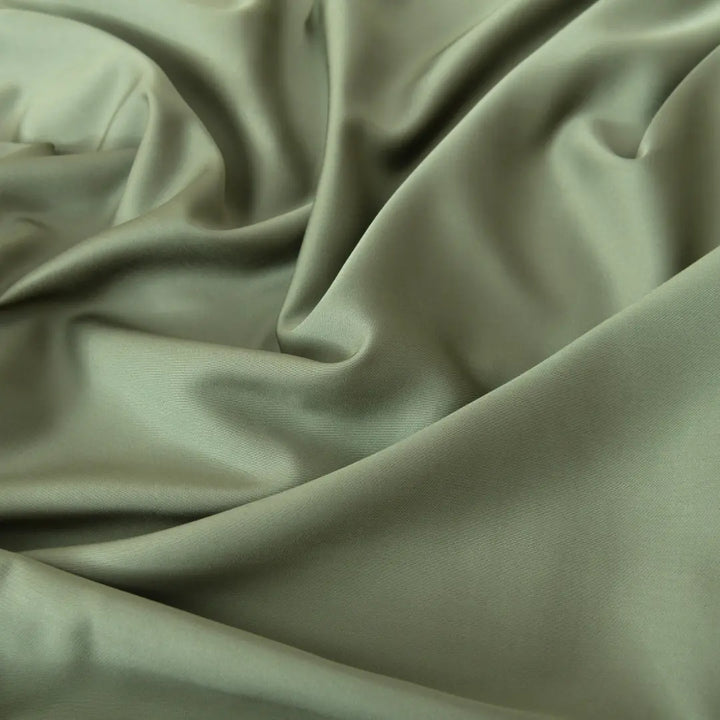 Elegant sage green, eco-conscious Linenly Moss Bamboo Fitted Sheets with gentle folds and a smooth, silky texture.