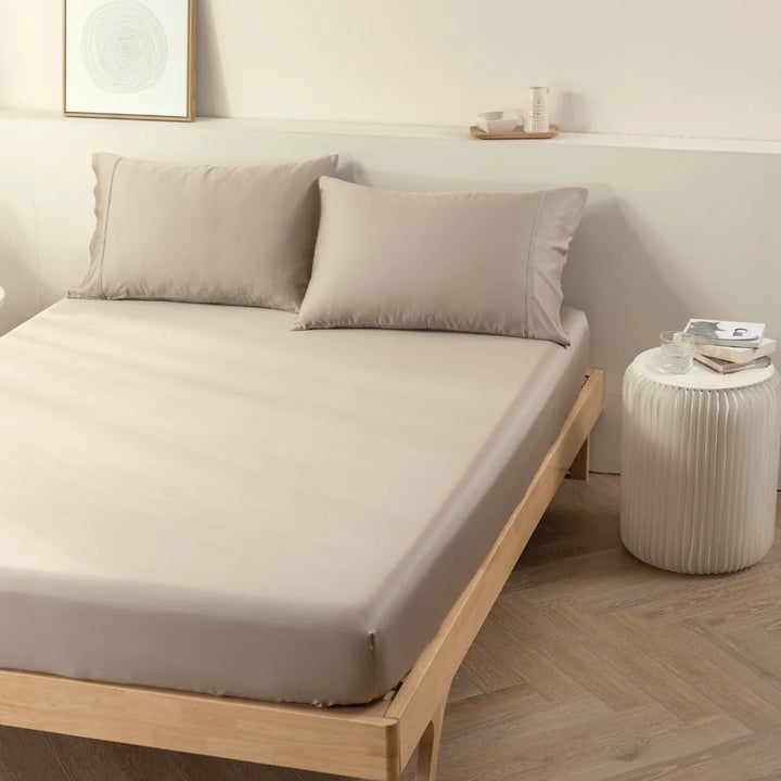 A neatly made bed with Linenly taupe bamboo fitted sheets in a minimalist bedroom setting, transforming it into a luxury sleep sanctuary.