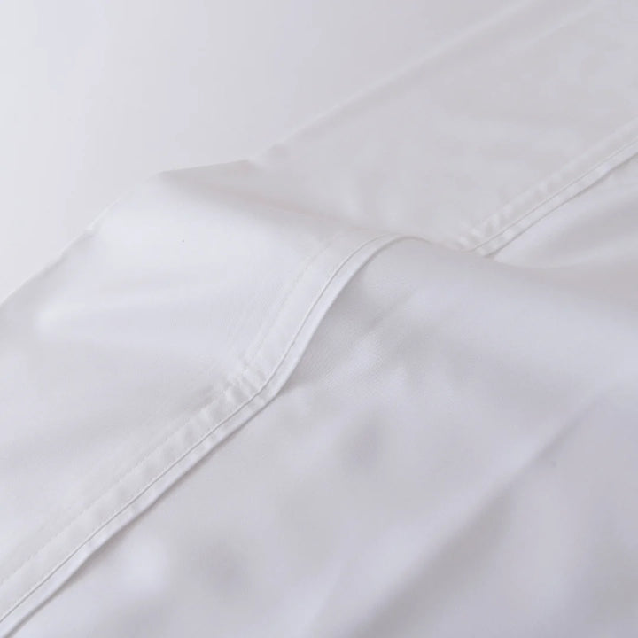 Close-up of a Linenly white bamboo fitted sheet with a seam, showcasing the texture and stitching detail on a plain background for luxury comfort.