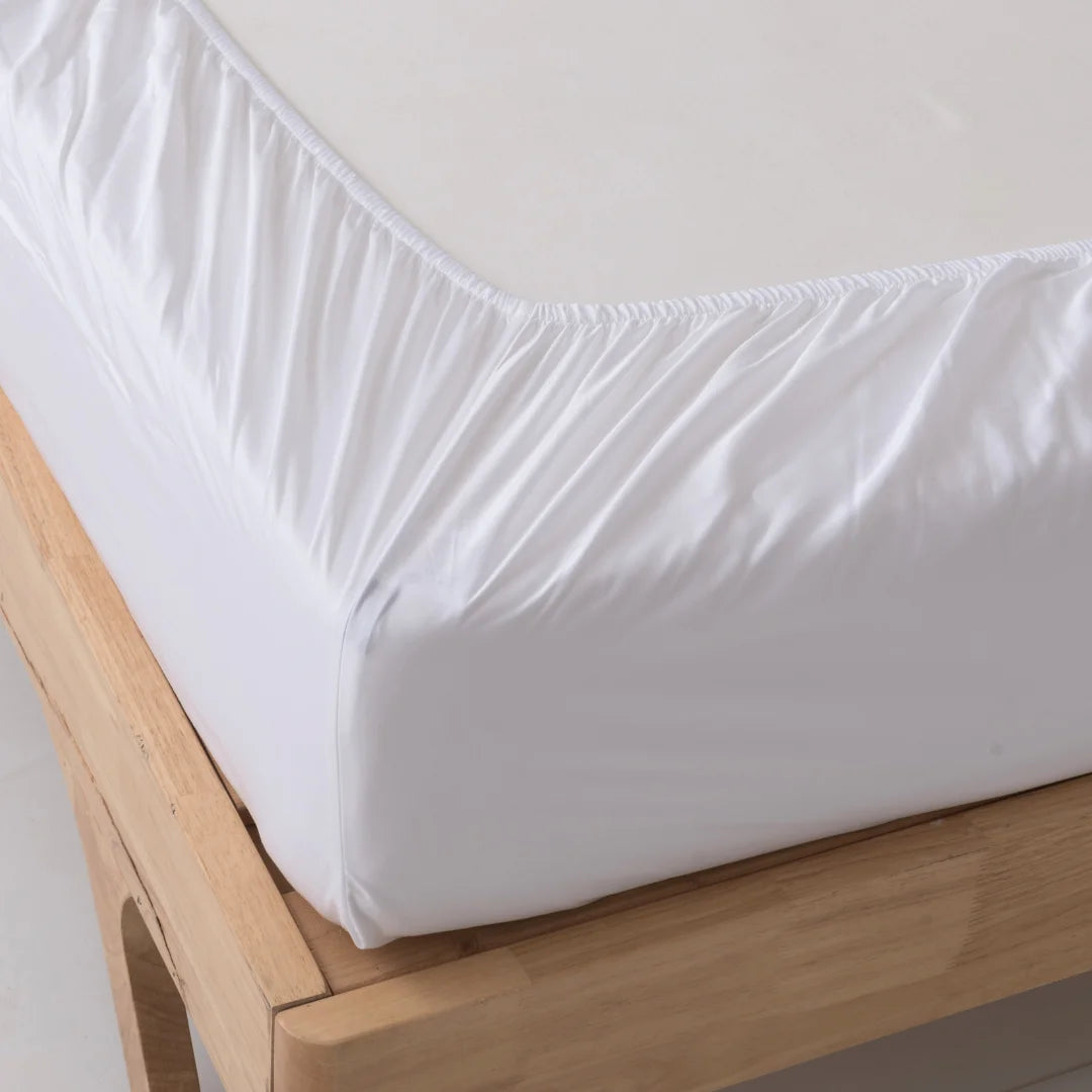 A neatly fitted Linenly white bamboo fitted sheet on a wooden bed frame, showcasing a clean and simple bedroom aesthetic.