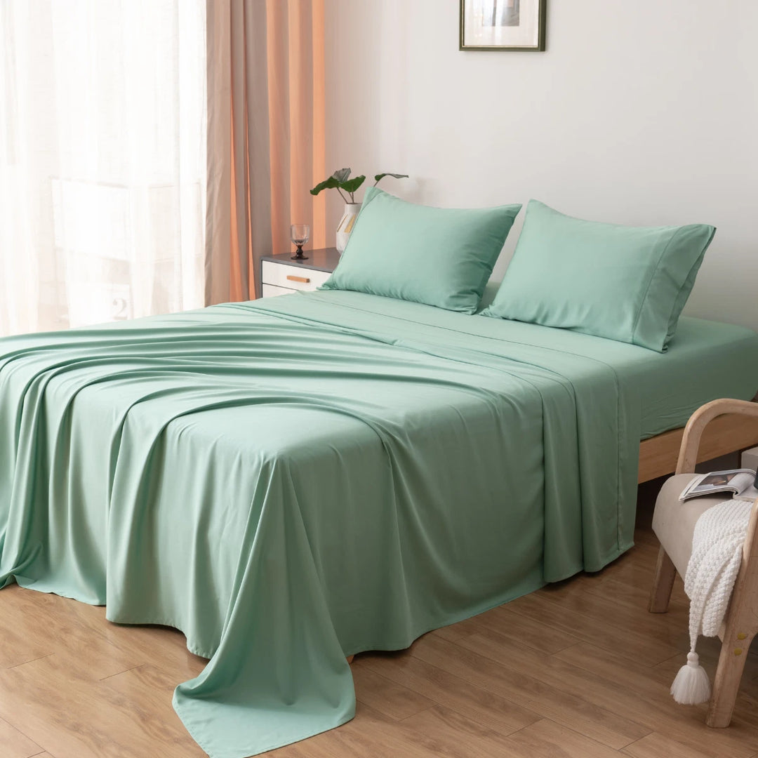 A neatly made bed with a soft seafoam green Bamboo Pillowcase Set - Green Sheen from Linenly, complemented by a matching pair of hypoallergenic pillows in organic bamboo pillowcases, in a bright room with a cozy ambiance