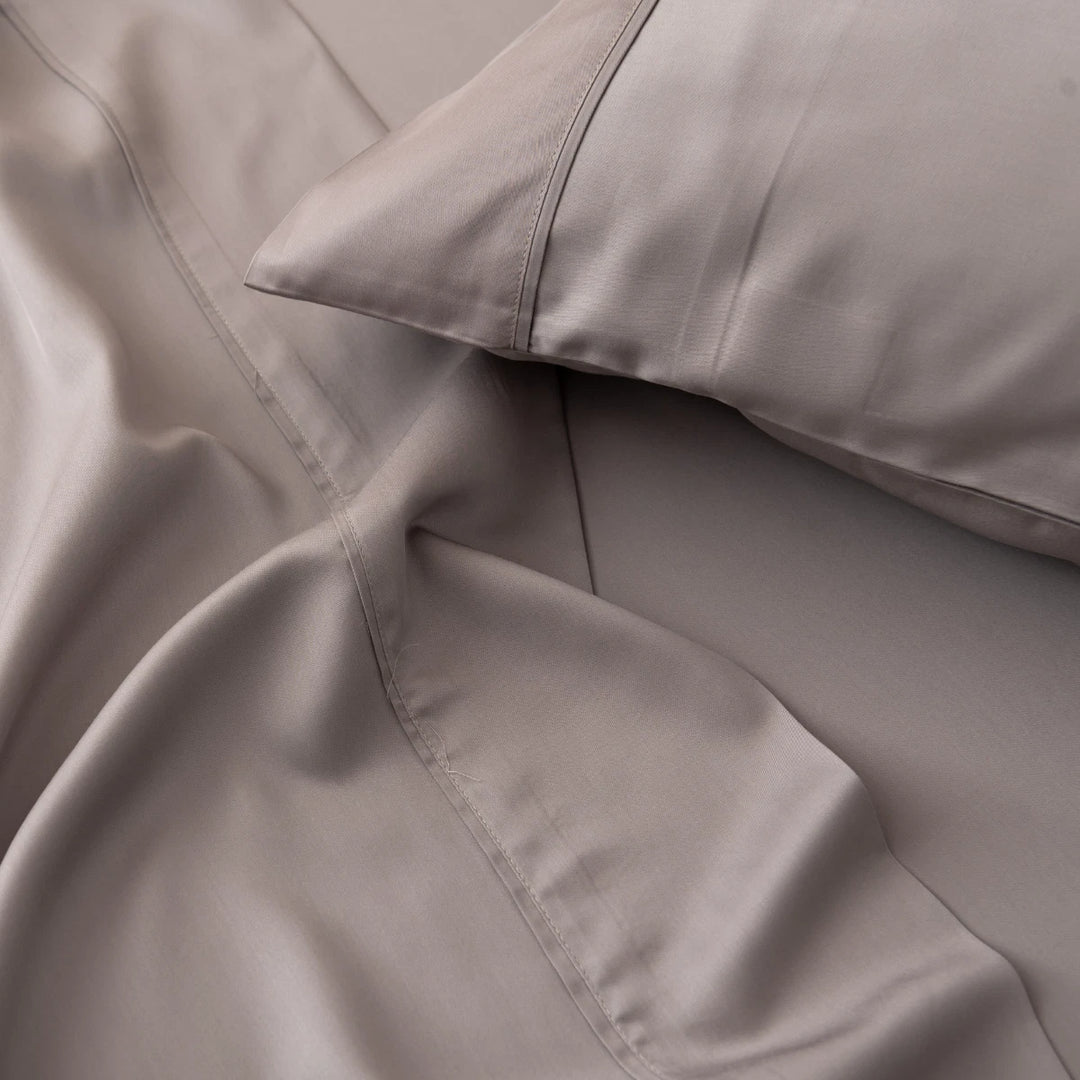 Luxurious grey satin bed linen set, with Linenly's Bamboo Pillowcase Set - Stone Terrace, emphasizing the soft texture and elegant stitching detail for a comfortable sleep.