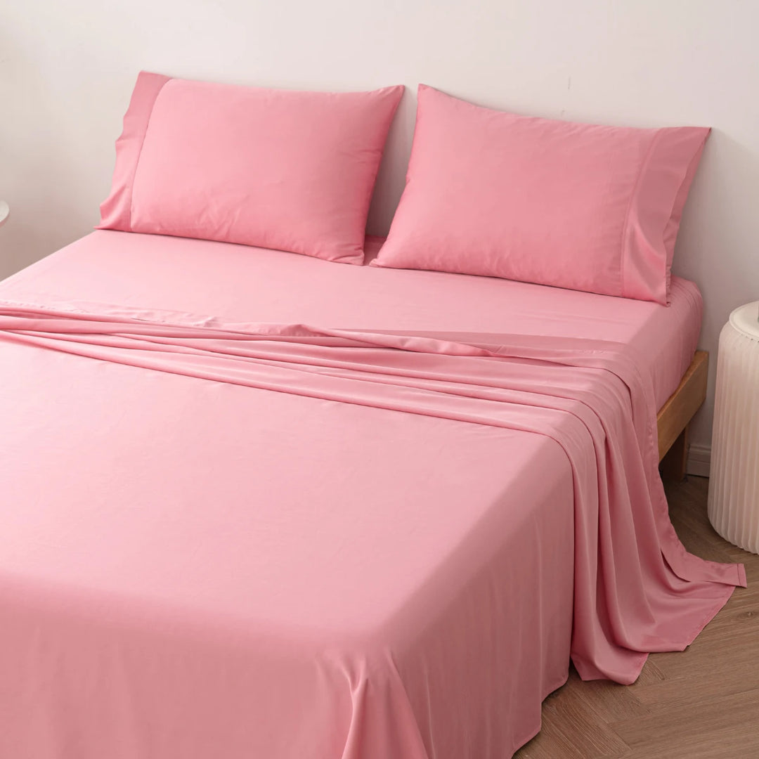 A neatly made bed with soft pink sheets and hypoallergenic Linenly bamboo pillowcases in a minimalistic bedroom setting.