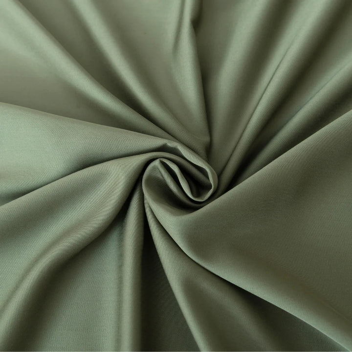An elegant swirl pattern created from a luxurious sage green fabric with a satin weave, highlighting the graceful folds and soft shadows is captured in the Linenly Bamboo Pillowcase Set in Moss.