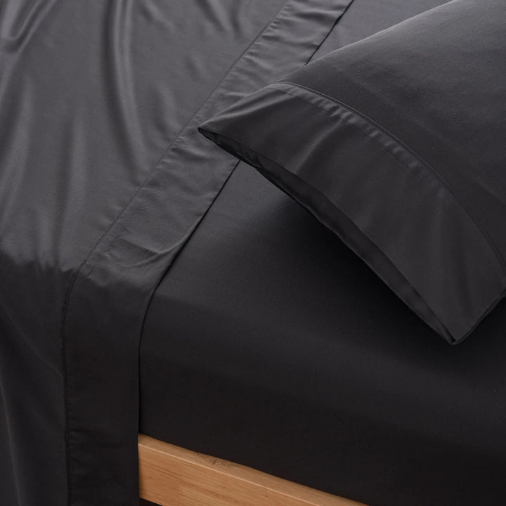 Close-up of a neatly made bed with a dark grey organic bamboo sheet and Linenly black bamboo pillowcases, giving a sense of luxury comfort in contemporary bedroom decor.