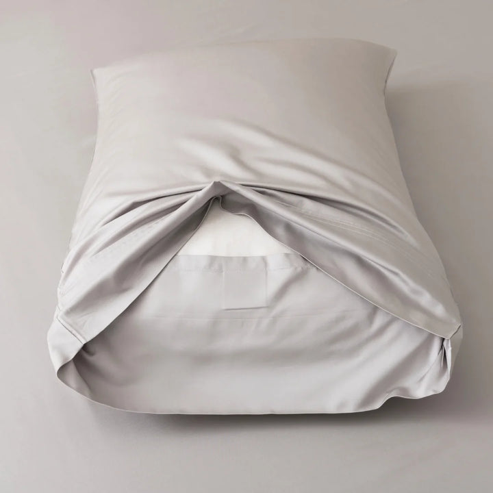 A neatly wrapped Linenly Silver Bamboo Pillowcase Set gift resembling a pillow on a light background.