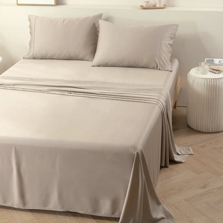 Neutral-toned bed with coordinating sheets and Linenly bamboo pillowcases in a serene bedroom setting.