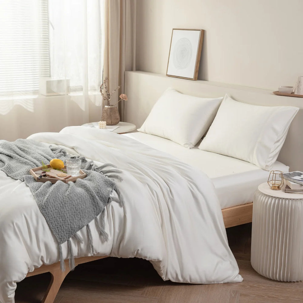 A cozy and inviting bedroom scene with a neatly made bed draped with a Linenly Ivory Bamboo Quilt Cover, a wooden breakfast tray with a morning cup of tea, all bathed in gentle natural light.