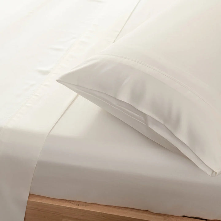 Crisp Linenly ivory bamboo sheet set neatly arranged on a bed with a focus on the smooth texture and the inviting fold of the pillowcase, showcasing its luxury bedding appeal.