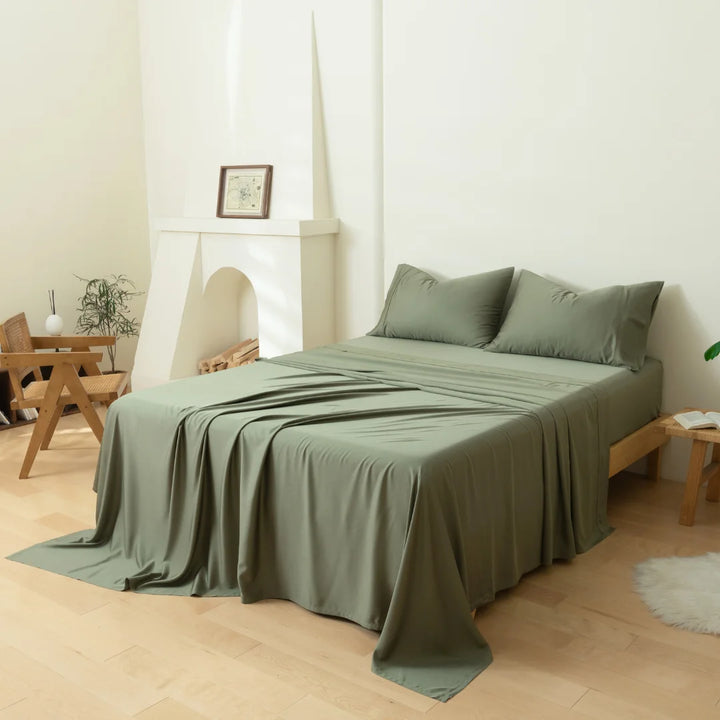 A neatly made bed with olive green, environmentally friendly Linenly Moss Bamboo Sheet Set in a serene, minimalist bedroom setting.
