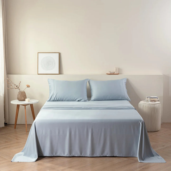 A neatly made bed with Linenly's Pale Blue Bamboo Sheet Set in a serene and minimalist bedroom setting, embodying sustainable practices.