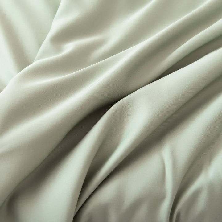 An elegant expanse of Linenly's Bamboo Sheet Set in Sage, made of luxuriously soft, sustainable bamboo fibers with soft folds creating a luxurious texture.