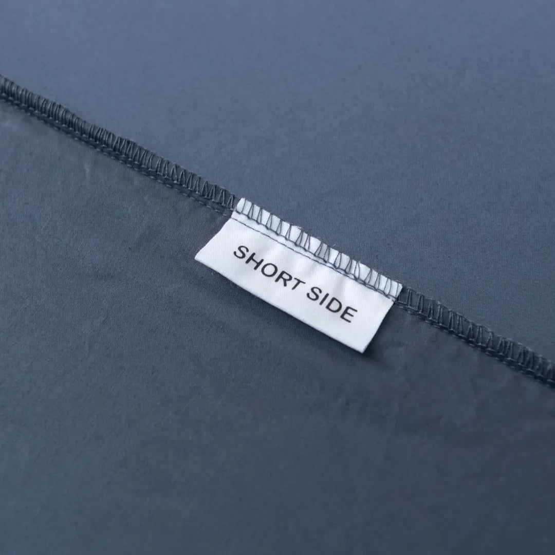 A close-up of a label on the Linenly Luxe Sateen Fitted Sheet - Midnight that reads "short side," indicating the orientation or a specific side of a textile product, such as bedding.