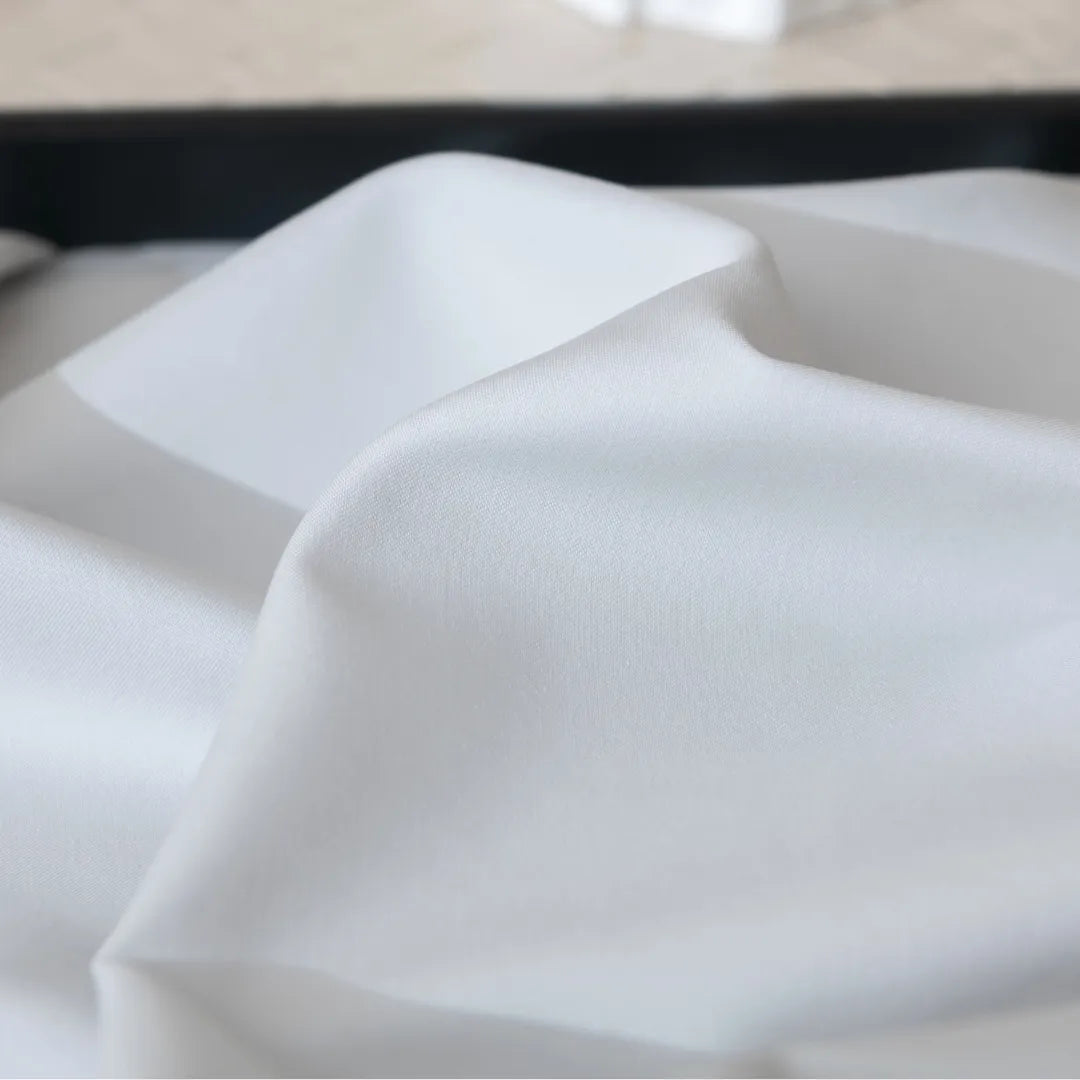 A close-up view of a Linenly Luxe Sateen Flat Sheet in Silver displaying shadows and highlights that create a subtle sense of depth and texture.