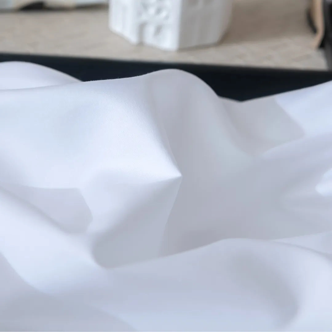 Gentle waves of a Linenly Luxe Sateen Flat Sheet in White flowing with serene elegance, crafted with a sateen weave.