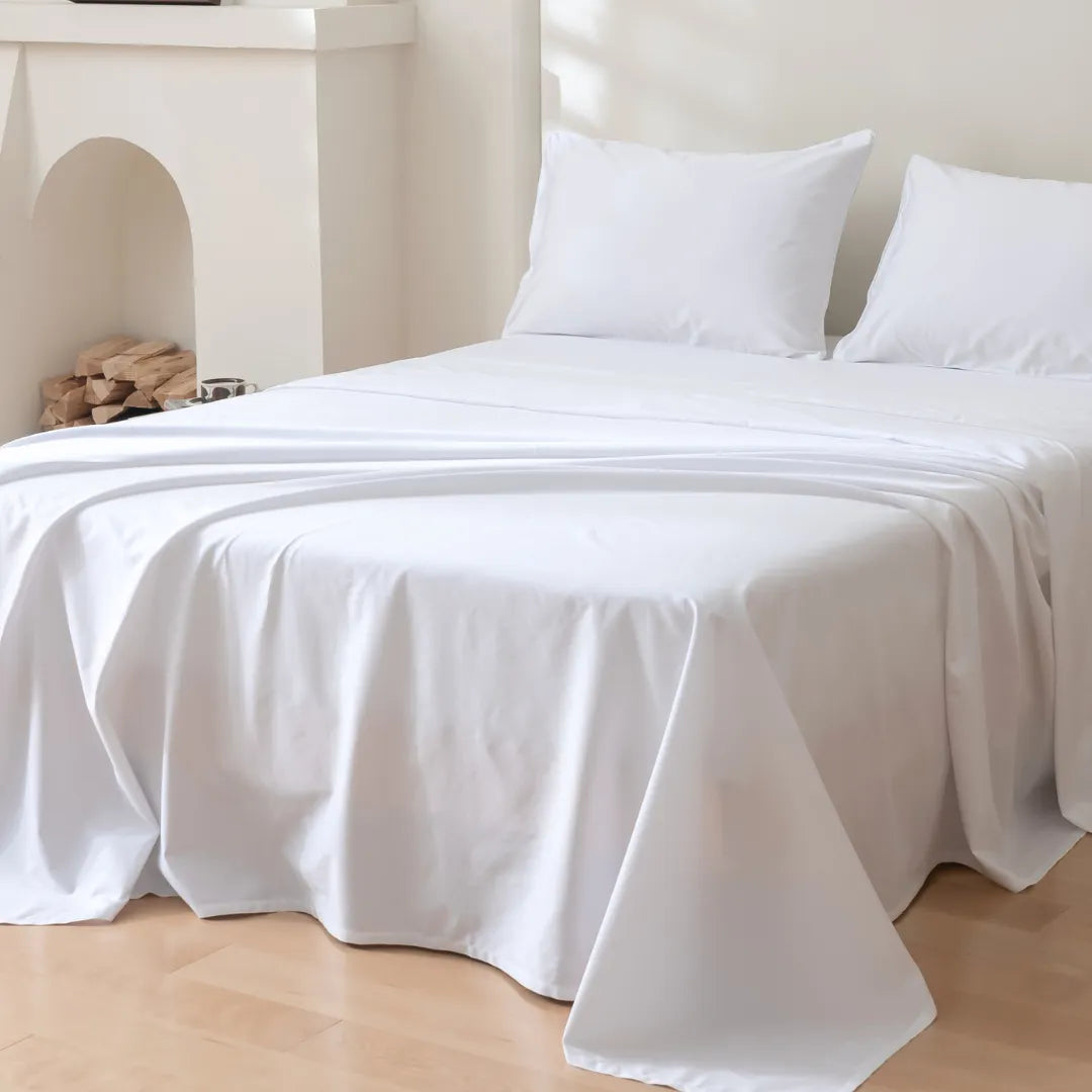 A neatly made bed with a Linenly Luxe Sateen Flat Sheet - White, featuring 500 thread count, long staple cotton in a serene bedroom setting.
