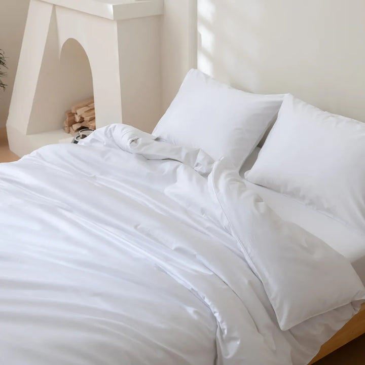 Crisp white Linenly Luxe Sateen flat sheet on a neatly made bed, bathed in soft natural light, inviting a peaceful rest.