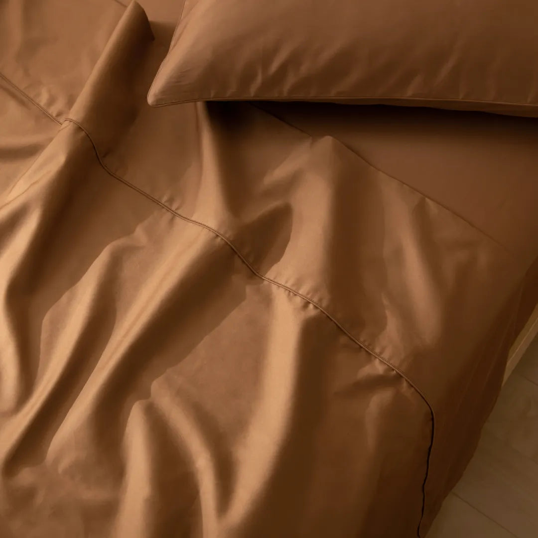 Elegant and smooth brown satin bedding with neatly stitched pillowcases, inviting a cozy and luxurious night's sleep under a Linenly Luxe Sateen Quilt Cover in Terracotta.