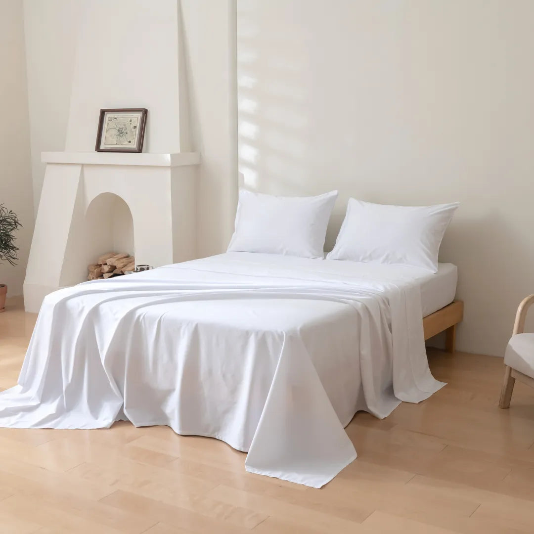 A minimalist bedroom with a neatly made bed, Linenly Luxe Sateen Sheet Set in White, and a serene, uncluttered ambiance.