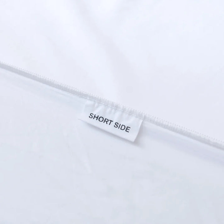 A Linenly Luxe Sateen Sheet Set - White with a label that reads "short side," indicating the orientation of the sheet for easier bed making.