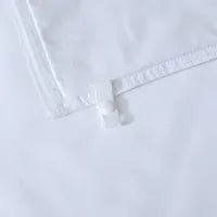 Close-up of a white fabric corner with a transparent plastic clip securing the edge, possibly part of bedding or a sheet.