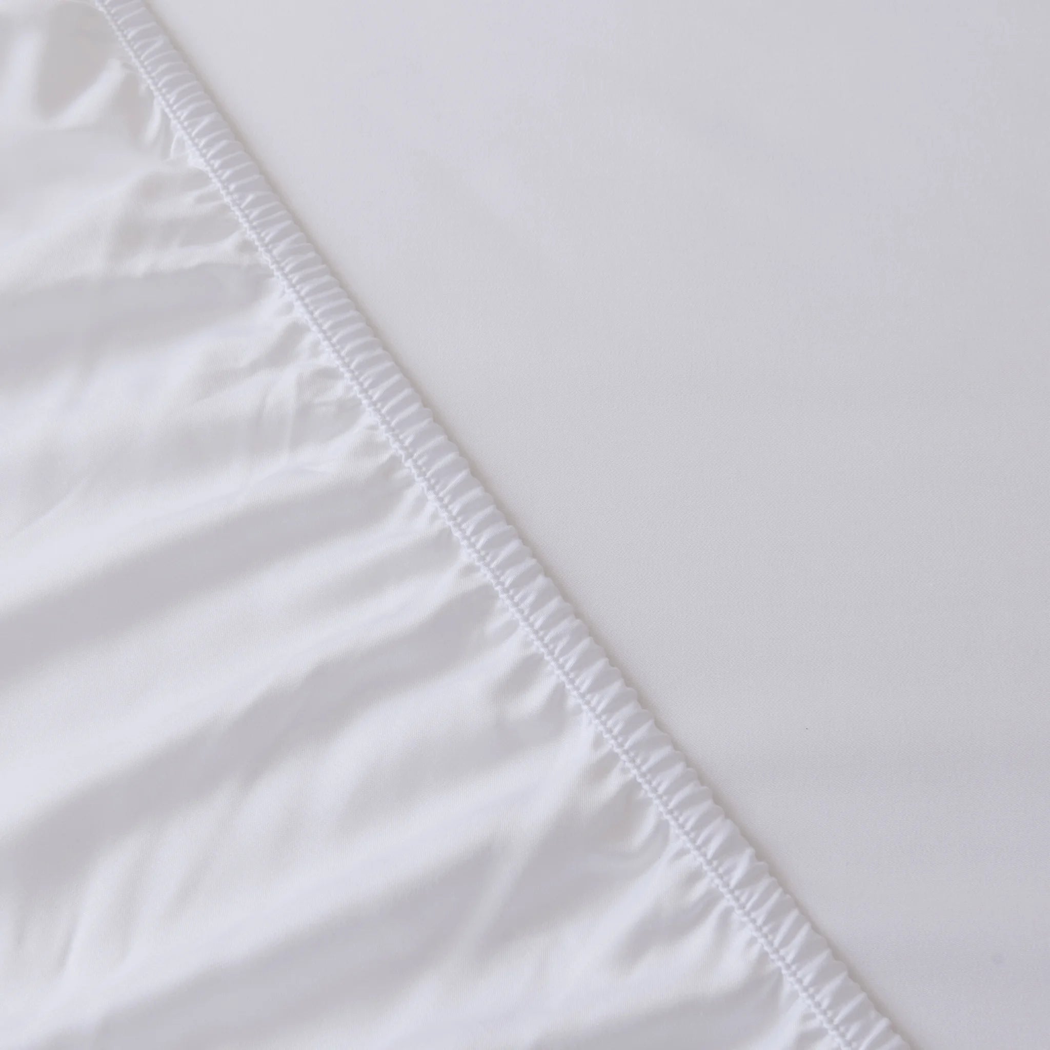 Close-up of the Linenly Bamboo Fitted Sheet - White, featuring deep sides with gathered elastic on one edge and smooth, luxurious softness for ultimate comfort.