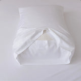 A Linenly Bamboo Pillowcase Set - White, shown with a white pillow partially inside and the open end facing forward, rests on a white surface.
